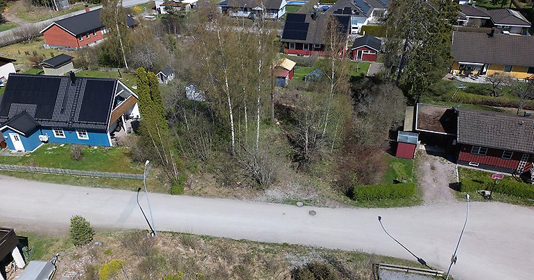 Drönarbild över aktuell tomt i Örbyhus med grönytor, hustak och gator.
