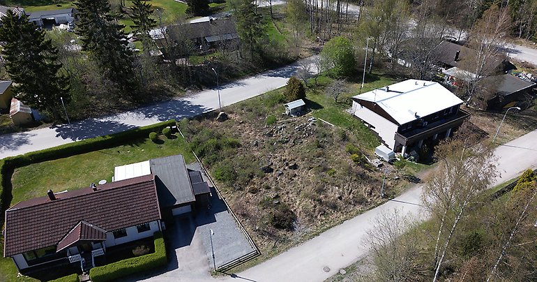 Drönarbild över aktuell tomt i Örbyhus med grönytor, hustak och gator.